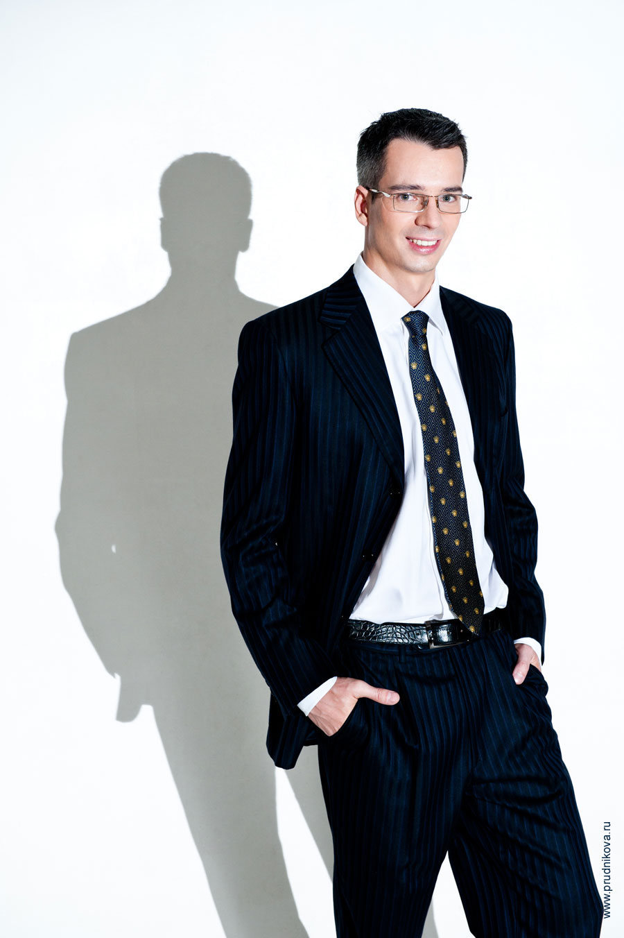 Модный мужской фотопортрет в деловом костюме с тенью сзади на белом фоне